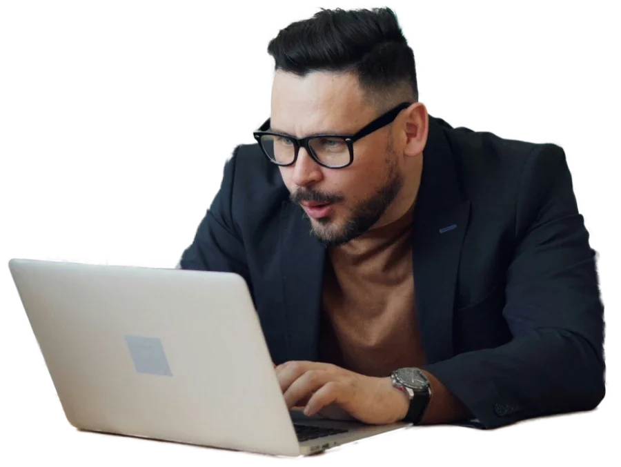 A man in glasses leaning in to read his laptop